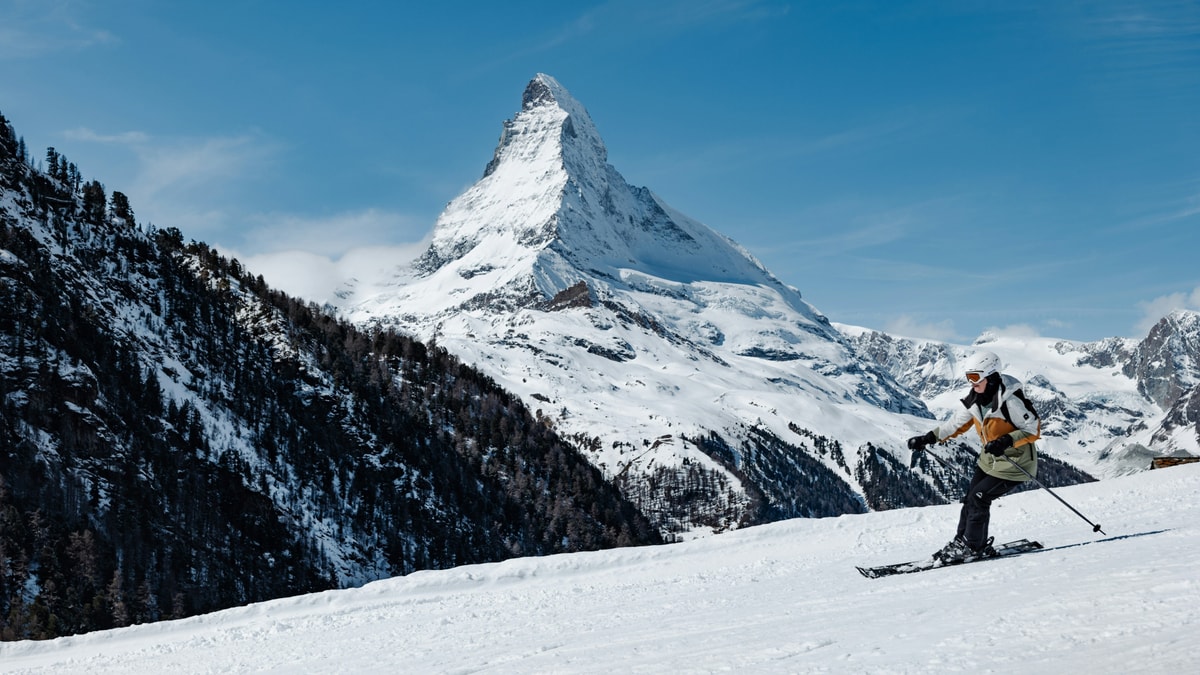 A skier carving a sunny piste with the Matterhorn behind